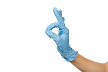 Mavi cerrahi eldivenli kadın doktor, beyaz arka planda onay işareti olduğunu gösteriyor.