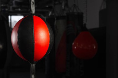 Boks salonundaki siyah-kırmızı kum torbası koyu bir arka planda. Rekabet, meydan okuma, çatışma veya iş liderliği için kırmızı kum torbası kavramını yumruklamak.