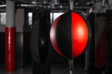 Boks salonundaki siyah-kırmızı kum torbası koyu bir arka planda. Rekabet, meydan okuma, çatışma veya iş liderliği için kırmızı kum torbası kavramını yumruklamak.