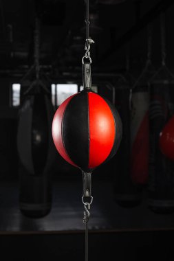 Boks salonundaki siyah-kırmızı kum torbası koyu bir arka planda. Rekabet, meydan okuma, çatışma veya iş liderliği için kırmızı kum torbası kavramını yumruklamak.