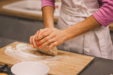Eller taze zencefilli kurabiye yapmak için mangırla çalışır. Kadın eli, ahşap bir masada un serpiştirilmiş ev yapımı kurabiyeler için hamur yapar. Kadınların elleri hamuru dışarı atıyor.