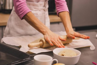 Eller taze zencefilli kurabiye yapmak için mangırla çalışır. Kadın eli, ahşap bir masada un serpiştirilmiş ev yapımı kurabiyeler için hamur yapar. Kadınların elleri hamuru dışarı atıyor.