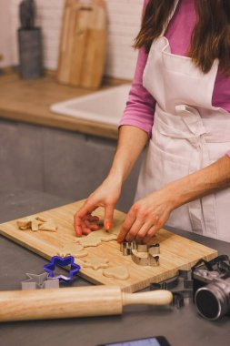 Evde, mutfakta Noel kurabiyesi yapıyorum. Kadınların elleri hamuru ahşap bir oklava ile yuvarlıyor ve yakınlarda da küfler var..
