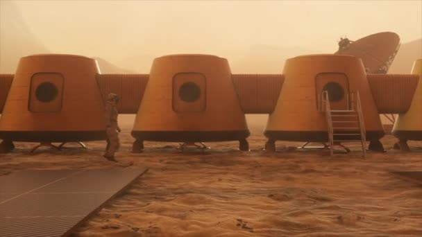 Űrhajós a Mars bolygón, kitérőt tesz a bázisa körül. Űrhajós sétál a bázison. Kis porvihar. A műholdantenna adatokat küld a földre. Realisztikus 3D animáció — Stock videók