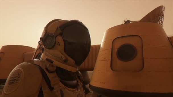 Astronauta en el planeta Marte, haciendo un desvío alrededor de su base. Astronauta caminando por la base. Pequeña tormenta de polvo. La antena parabólica envía datos al suelo. Animación 3D realista — Vídeo de stock