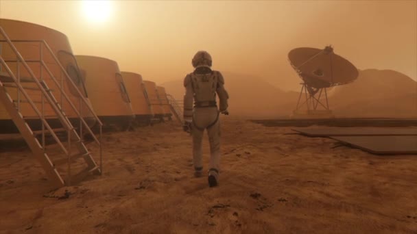 Astronaute sur la planète Mars, faisant un détour autour de sa base. Astronaute marchant le long de la base. Petite tempête de poussière. La antenne satellite envoie des données au sol. Animation 3D réaliste — Video