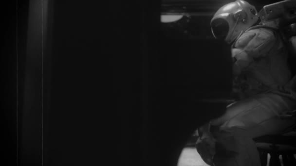 Astranaut in een ruimtepak speelt piano in een ruimteschip met uitzicht op de planeet aarde. Ruimte en muziek concept. Oud film effect. Zwart op wit. 3D-animatie — Stockvideo