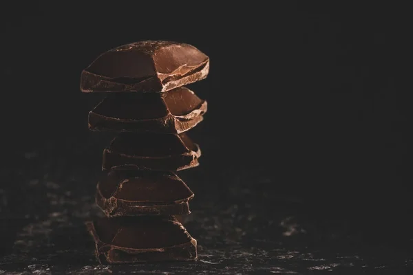 Blocchi di cioccolato fondente rotto stack su sfondo nero — Foto Stock