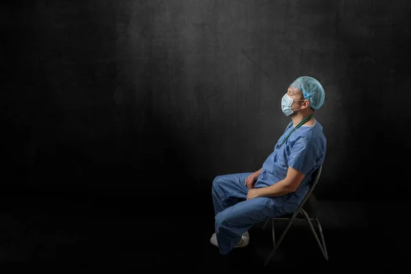 Smutny, wyczerpany lekarz siedzący w ciemnym pokoju — Zdjęcie stockowe