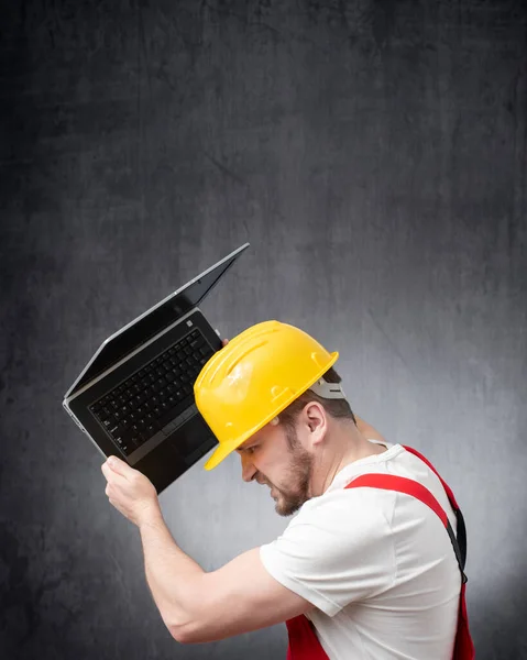 Angry construction worker trying to break his laptop
