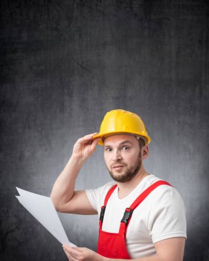 Elinde belge tutan kafası karışık bir inşaat işçisi.