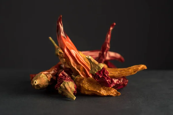 Peperoncini secchi rossi e gialli su fondo scuro — Foto Stock
