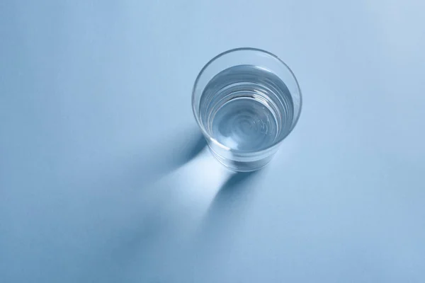 Вид сверху стакана чистой питьевой воды на синем фоне — стоковое фото