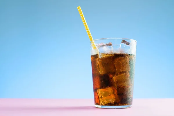 A glass of cola with ice on blue and pink background — Stock Photo, Image