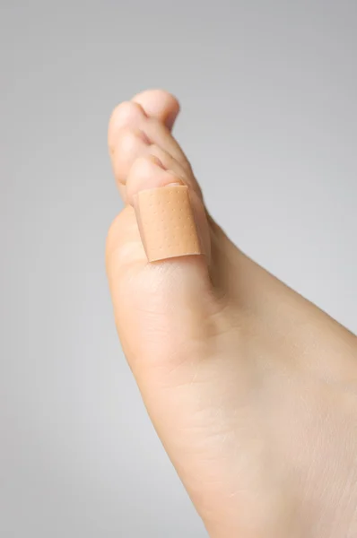 Closeup of a plaster on female toe — Stock Photo, Image