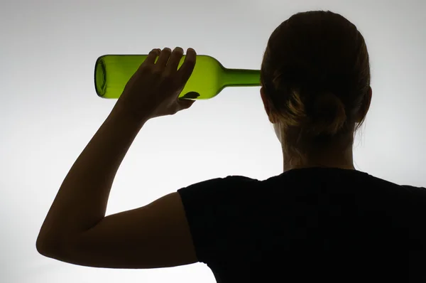 Silueta de un alcohólico con una botella —  Fotos de Stock