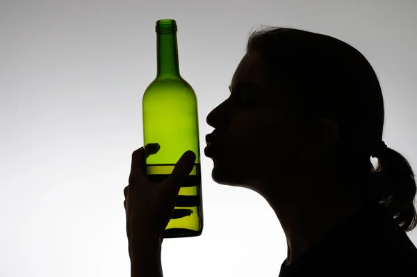 Alcoholic woman kissing a wine bottle — Stock Photo, Image