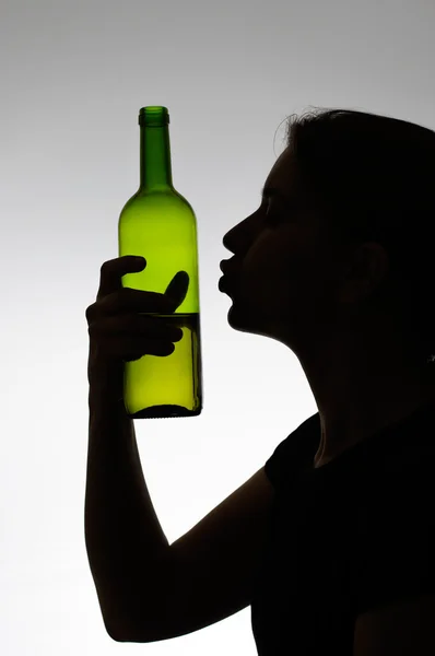Alcoholic woman kissing a wine bottle — Stock Photo, Image