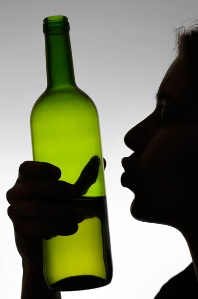 Alcoholic woman kissing a wine bottle — Stock Photo, Image