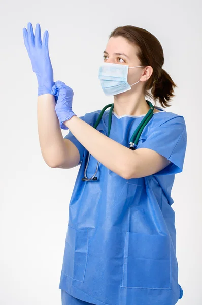 Mavi cerrahi eldiven koyarak doktor