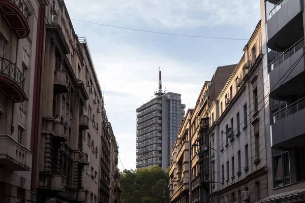 在一个阳光明媚的下午 位于塞尔维亚首都贝尔格莱德市中心的一座由混凝土和一座70年代高耸的钢结构摩天大楼建成的古老住宅 — 图库照片