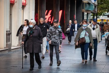 BELGRAD, SERBIA - 29 Ağustos 2020: Yaşlı kadın Coronavirus Covid 19 krizinde maske takmayan genç bir adamın yanında yüz maskesi koruyucu ekipmanlarla yürüyor