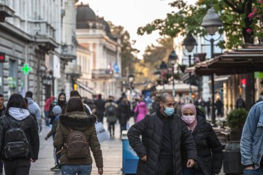 BELGRAD, SERBIA - 10 Ekim 2020: Bir çift, Arap, ortadoğu, Belgrad caddesinde yürüyen ve Coronavirus Covid 19 kriz donanımında yüz maskesi takan bir kadın