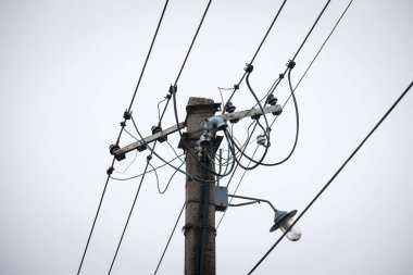 Eski bir elektrik hattı ve bir sokak lambası, bir güç kaynağı kablosu ile, bulutlu bir öğleden sonra kamu elektrik ağıyla eski bir bağlantı sisteminden yapılmış.