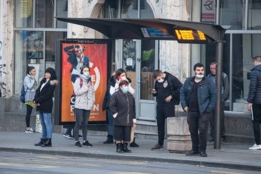 BELGRAD, SERBIA - NOVEMBER 8, 2020: Coronavirus Covid 19 krizinde maske koruyucu ekipman takan genç ve yaşlı kadın ve erkek kalabalığı, Belgrad 'da durakta otobüslerini bekliyor