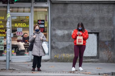 BELGRAD, SERBIA - 14 Kasım 2020: Belgrad bulvarında karşıdan karşıya geçmek için bekleyen yaşlı ve genç kadınlar Coronavirus Covid 19 krizinde maske koruyucu ekipman giyiyorlar