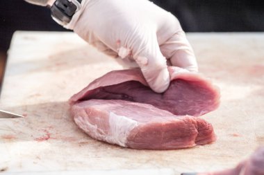 Profesyonel bir kasapın elleri, Sırbistan 'ın kırsal kesiminde uzun bir bıçakla beyaz bir tahtada çiğ domuz eti kesiyor. Domuz eti Sırbistan 'ın en büyük üretimlerinden biri