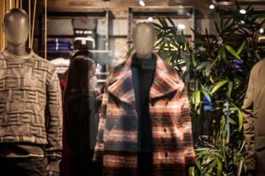 BELGRAD, SERBIA - 12 Kasım 2020: Coronavirus covid 19 krizi sırasında Belgrad 'da bir moda perakende giyim mağazasında kot pantolon katlayan personel çalışanı