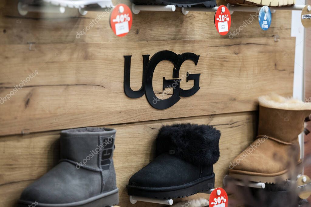 BELGRADE, SERBIA - DECEMBER 8 2020: Ugg logo in front of some of their boots for sale in a shop. Ugg is an american footwear brand known for their sheepsking boots