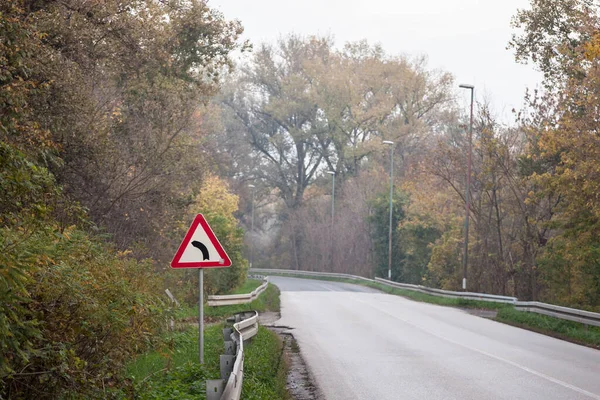 森林柏油路上的欧洲弯道路标 其典型的标准三角形路标指示着前面的弯道 — 图库照片
