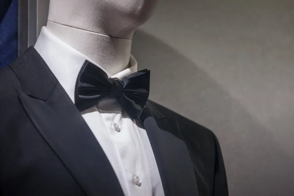 Selective blur of a dummy wearing a black tuxedo, a white shirt and a black bowtie. it is a typical male suit and costume for formal events.
