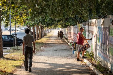 BELGRAD, SERBIA - 21 AĞUSTOS 2018: Billsticker veya Billposter, Belgrad 'daki Novi Beograd iş merkezinin duvarına reklam afişleri asıp duruyor