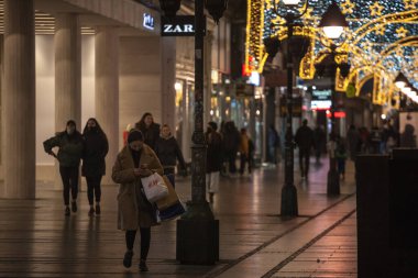 BELGRAD, SERBIA - 12020 ARALIK: Kneza Mihailova sokaklarında Coronavirus covid 19 krizi, noel ışıklarıyla aydınlatılmış yüz maskesi takan insanlar için seçici bulanıklık
