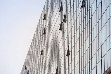 Ayna pencereli bir finans binasının soyut cephesi. Bazıları ofisin içine hava girmesi için açılıyor.