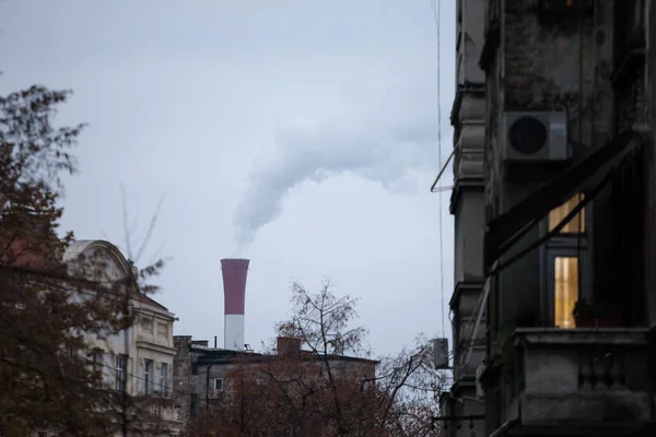Industrial red chimney of a factory working and releasing toxic fume and smokes in the atmosphere surrounded by residential buildings in Belgrade, Serbia
