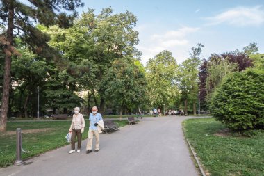BELGRAD, SERBIA - 14 Mayıs 2020: Yaşlı yaşlı erkek ve kadın, çift, Coronavirus Covid 19 sağlık krizi sırasında Belgrad 'da bir parkta uyanan, solunum maskesi takan yaşlı erkek ve kadın seçici bulanıklık