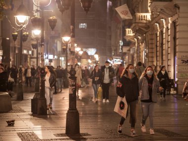 BELGRAD, SERBIA - 28 Ekim 2020: Coronavirus covid 19 krizi üzerine Belgrad 'ın Kneza Mihailova caddesinde kışın solunum maskesi takarak yürüyen iki kız, genç kadın ve arkadaş seçici bulanıklık