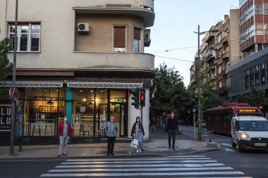 BELGRAD, SERBIA - 12 Mayıs 2020: Yaşlı adam ve genç kadın Coronavirus Covid 19 krizinde maske koruyucu ekipman takmış bir cadde trafiğine yürüyor ve bakıyor