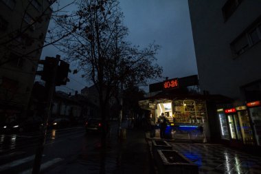 BELGRADE, SERBIA - DECEMBER 8, 2018: Convenience store, a kiosk, open non stop 24/7 selling essential goods and press newspaper, during a dark evening with clients in front. It is as well called trafika