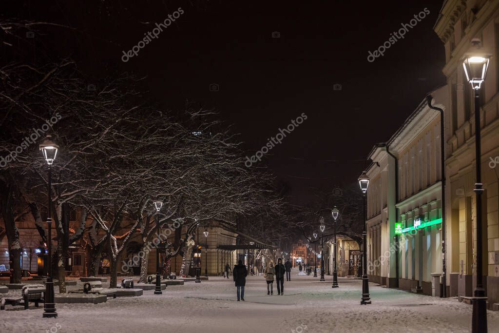PANCEVO, SERBIA - 17 DE ENERO DE 2021: Pareja, amantes, caminando en la nieve entre la plaza principal y la calle principal de Pancevo, durante una noche nevada de invierno en la PANCEVO, SERBIA - 17 DE ENERO DE 2021: Pareja, amantes, caminando en la nieve entre la plaza principal y la calle principal de Pancevo, durante una noche nevada de invierno en la