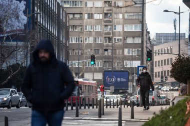 BELGRAD, SERBIA - 14 Şubat 2021: Coronavirus covid 19 sağlık krizi sırasında Belgrad sokaklarında solunum maskesi takan genç adamın seçici bulanıklığı