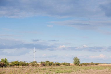 Aktarım kuleleri, direkler, güç kuleleri, yüksek voltajlı elektrik taşımacılığı ve dağıtımı için uyarlanmış, tarımsal arka planda kullanılmayan alanlar önünde