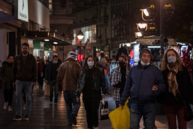 BELGRAD, SERBIA - 30 Ekim 2020: Coronavirus Covid 19 krizinde yüz maskesi koruyucu ekipman takmış bir kalabalığın içinde yürüyen bir kadın, genç kız, seçici bulanıklık
