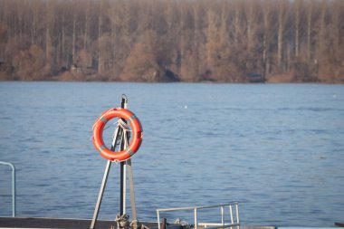 Turuncu can simidi denizin yanındaki bir nehirde asılı duruyor. Bu cankurtaran boğulma durumunda ve cankurtaranlar için insanları korumak için kullanılır.