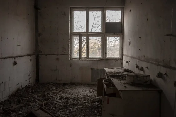 Interior of an abandoned office building, in a dirty and damaged room, with an old desk remaining after the closure and the bankruptcy of the business.