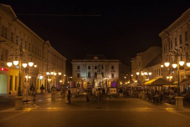 SZEGED, HUNGARY - 20 Temmuz 2017: Yazın Szeged şehir merkezinde, Kossuth Lajos Heykeli yakınlarındaki Klauzal ter meydanında yürüyen seçici bulanık insanlar,